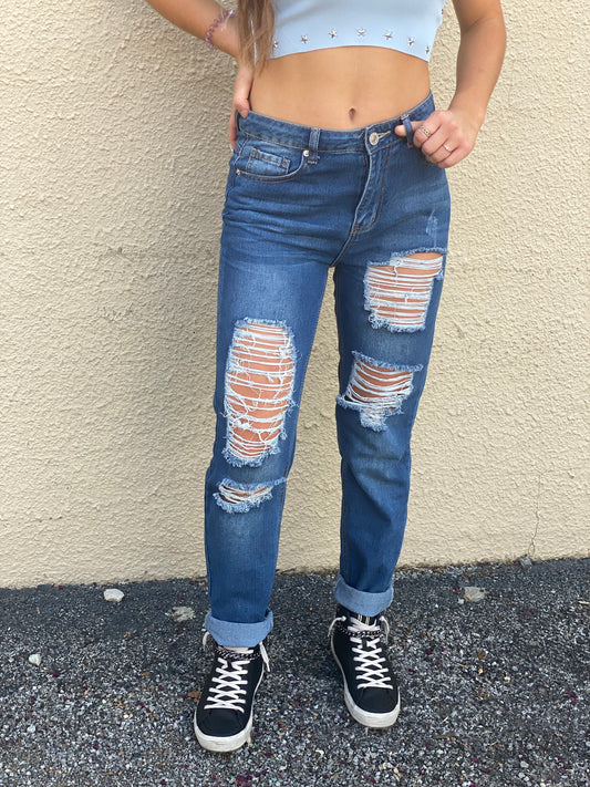 Boyfriend jeans featuring lightweight medium dark wash denim material with ultra distressed detailing